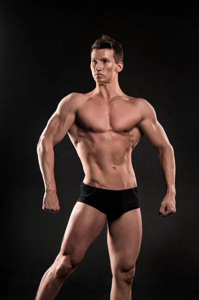 Homme athlète montrer corps musculaire sur fond sombre — Photo