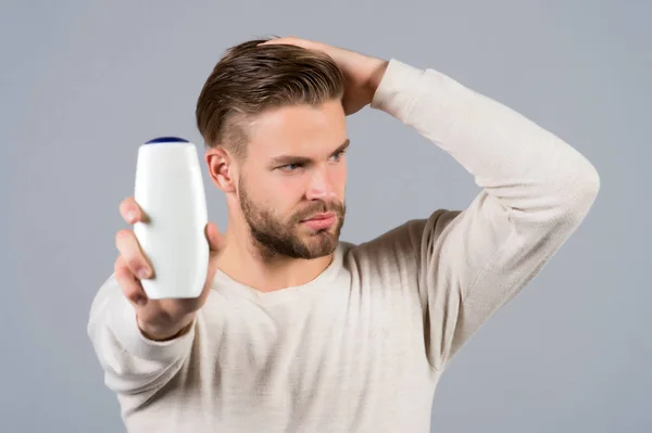 Hombre tacto cabello sano con botella de champú en la mano — Foto de Stock