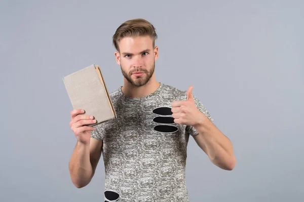 Uomo studente con libro spettacolo pollice in su mano gesto — Foto Stock
