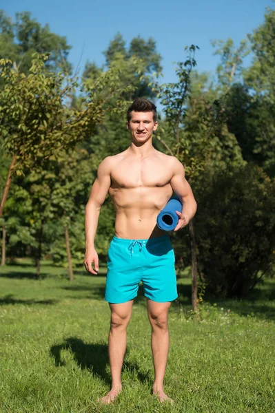 Atlet gülümseme ile mavi yoga mat elinde — Stok fotoğraf