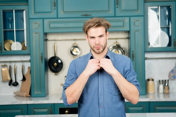 Macho in blauw shirt fix kraag op keuken — Stockfoto