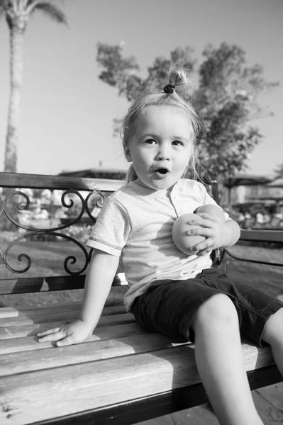 Amazed child sitting with two oranges on bench — Stock Photo, Image