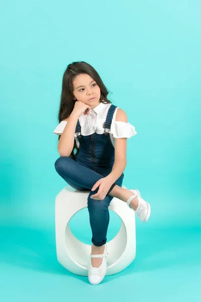Kind mit nachdenklichem Gesicht sitzt auf Stuhl auf blauem Hintergrund — Stockfoto