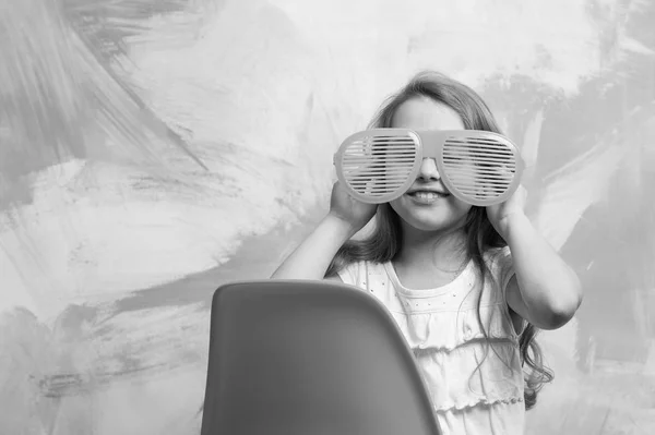 Glückliches Kind sitzt auf orangefarbenem Stuhl in Sommerbrille — Stockfoto