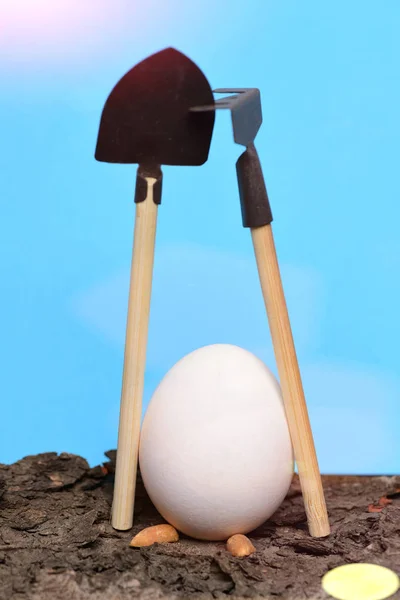 Colore bianco uovo di Pasqua con pala e rastrello su corteccia — Foto Stock