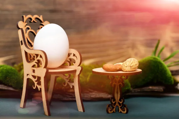 Påsk ägg i trä stol på bord med nötter, moss — Stockfoto