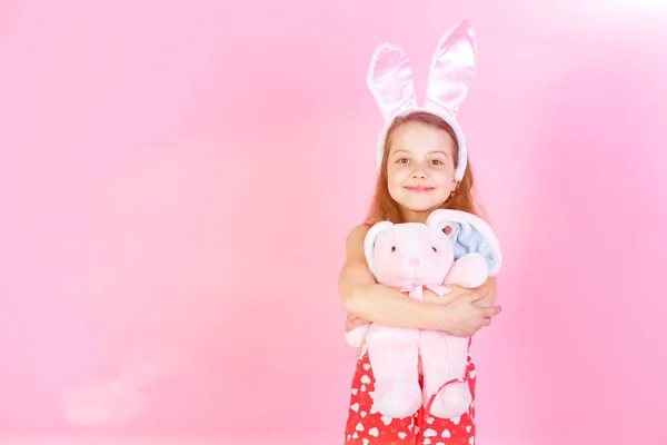 在粉色背景下抱着兔子玩具的快乐女孩 — 图库照片