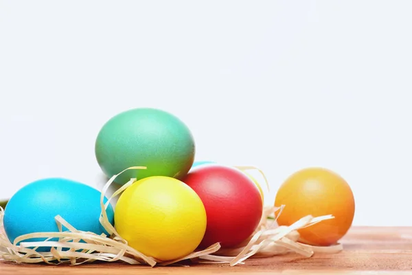 Huevos coloridos de Pascua pintados con nido de paja aislado en blanco — Foto de Stock