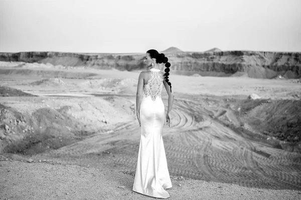 Woman in white dress in sand dunes.