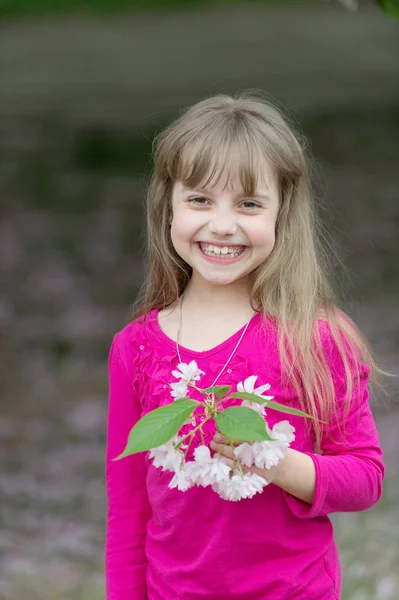 Liten flicka håller våren sakura blomma — Stockfoto