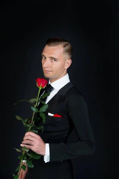 Man met rode roos op donkere achtergrond — Stockfoto