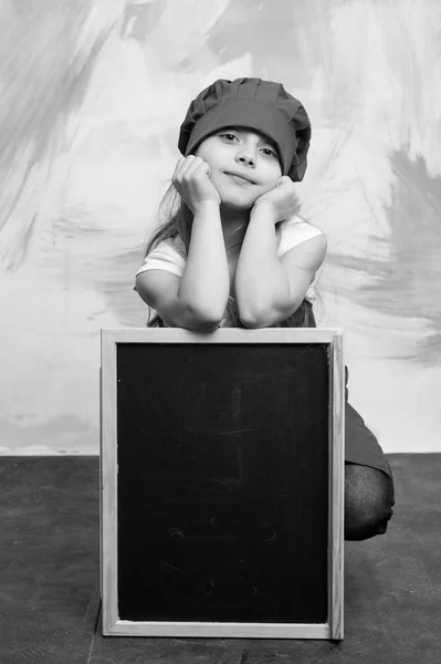 小さな女の子が黒板と帽子で調理します。. — ストック写真
