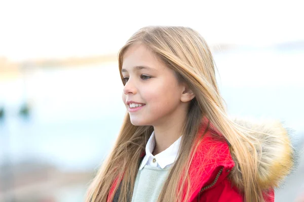 Sonrisa infantil en un ambiente borroso. Chica con el pelo largo rubio en el otoño día al aire libre. Concepto de infancia feliz. Moda y estilo infantil. Belleza, look, peinado . — Foto de Stock