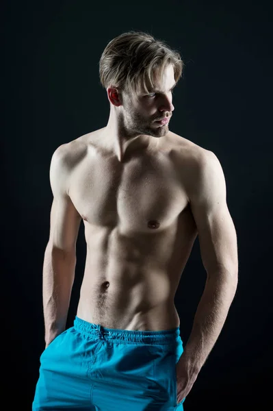 Uomo atleta mostra busto muscolare in pantaloncini blu — Foto Stock