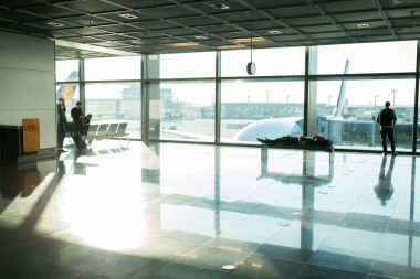 Frankfurt am Main, Almanya - 11 Ekim 2015: insanlar için büyük pencere cam havaalanında uçuş için bekleyin. Turizm yolcu çanta, Bagaj lounge salonunda. Yolculuk tutkusu, tatil, seyahat
