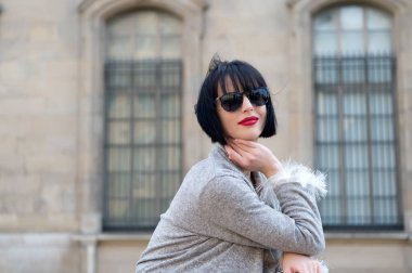 Güneş gözlüklü şehvetli kadın Paris, Fransa, moda pozu veriyor. Esmer saçlı, kırmızı dudaklı, makyajlı, güzel bir kadın. Moda, aksesuar, moda. Güzellik, bak, makyaj. Cilt bakımı, saç şekli, tarzı
