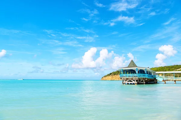 Playa de mar con refugio de madera en día soleado en antigua. Muelle en agua turquesa sobre fondo azul cielo. Vacaciones de verano en el Caribe. Vagabundo, viaje, viaje. Aventura, descubrimiento, viaje — Foto de Stock