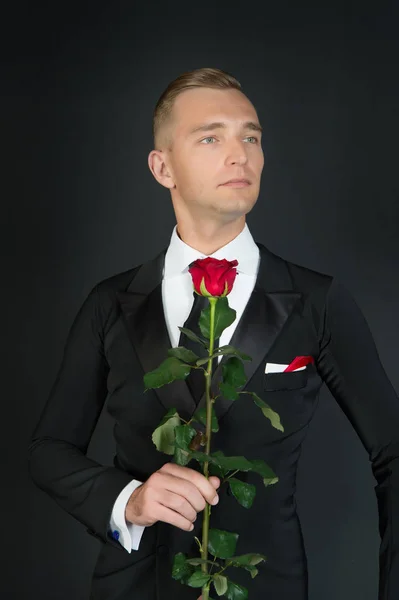 Чоловік у костюмі з трояндою на темному тлі — стокове фото