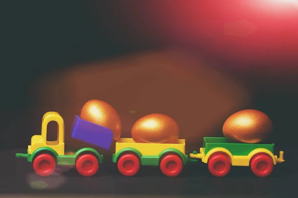 Traditional golden eggs in plastic colorful car toy or locomotive — Stock Photo, Image