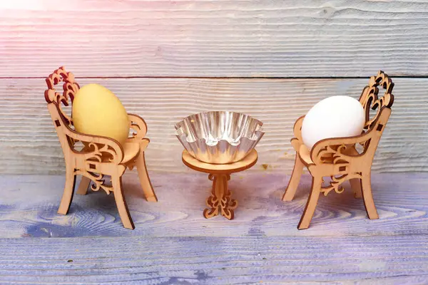 Påsk ägg i trä stolar vid bord med metalliska skål — Stockfoto