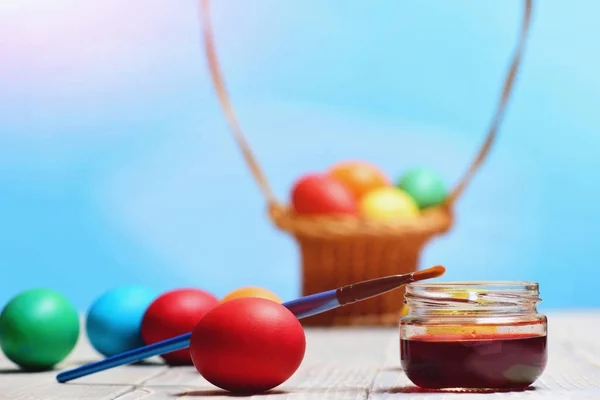 paint jar with paintbrush and colorful easter eggs in basket