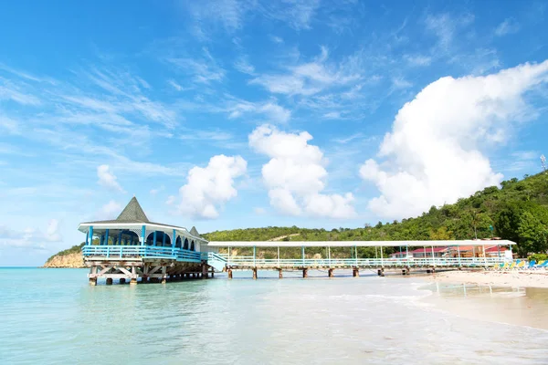 码头在蓝绿色的水在蓝天背景。在安提瓜阳光明媚的日子, 海边有木制的庇护所。加勒比的暑假。流浪, 旅行, 旅行。探险, 发现, 旅程 — 图库照片