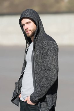 Kapüşonlu sakallı maço açık havada, moda. Adam eşofman üstü giyer, gündelik tarzda. Erkek modası, tarz, spor giyim. Aktif ve sağlıklı insanlar için yaşam tarzı, spor