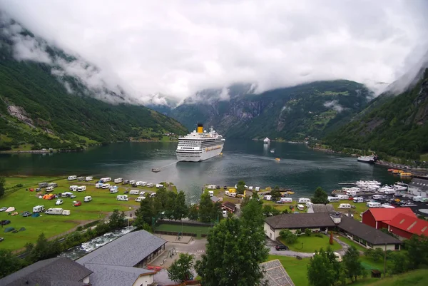 Geiranger, Noruega - 25 de enero de 2010: vacaciones, viaje, ansia de viajar. Nave en fiordo noruego en cielo nublado. Transatlántico en el puerto del pueblo. Destino de viaje, turismo. Aventura, descubrimiento, viaje . — Foto de Stock