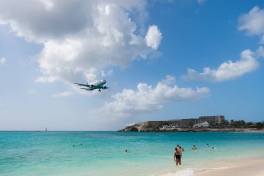 Philipsburg, Sint Maarten - 13 Şubat 2016: arazi maho sahil boyunca uçak. Jet Uçuş bulutlu gökyüzü düşük sinek. Mavi deniz uçakta. Caribbean Beach Tatil. Yolculuk tutkusu, seyahat ve gezi