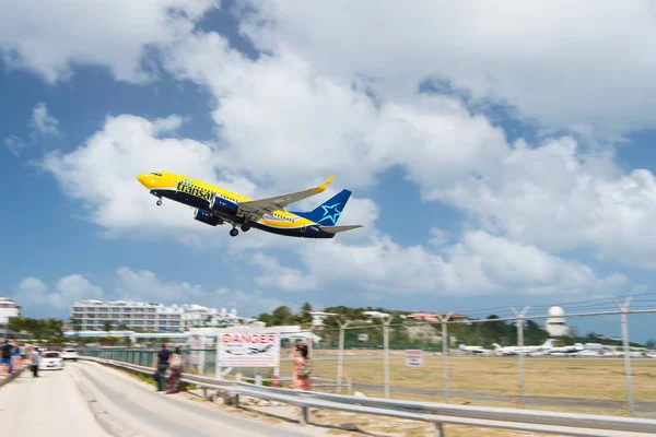 Philipsburg, Sint Maarten - February 13, 2016: plane low fly over maho beach. Jet flight land on cloudy blue sky. Airplane in sunny clouds. Beach vacation at Caribbean. Wanderlust, travel and trip — Stock Photo, Image