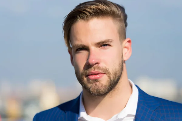 Mann mit bärtigem Gesicht auf sonnigem Außengelände. Geschäftsmann mit stylischem Haarschnitt am verschwommenen Himmel. Business-Mode, Stil und Trend. Pflege und Haarpflege im Friseursalon — Stockfoto