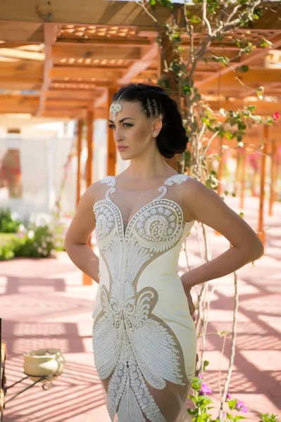 Donna sensuale in abito da sposa bianco con perline di perle. Donna con diadema di gioielli su capelli castani. Sposa con viso truccato. Bellezza ragazza con look glamour e trucco. Moda stile modello e acconciatura — Foto Stock