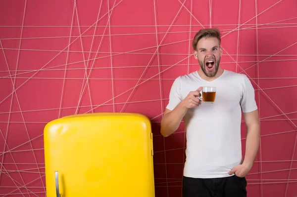 Hombre sostenga la taza de té o café en la cocina. Bostezo macho somnoliento en la nevera retro. Licenciado con bebida de la mañana en el refrigerador. Desayuno, refresco y energía. Dieta saludable para el resfriado o la gripe — Foto de Stock