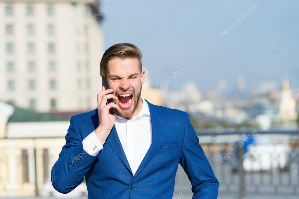 Happy manager talk on smartphone. Man with mobile phone on sunny terrace. Businessman in blue suit outdoor. Business communication, new technology and sms. Modern life and business lifestyle