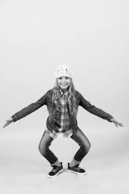 Kot elbiseli, şapkalı, ekose gömlekli çocuk gülümsüyor.