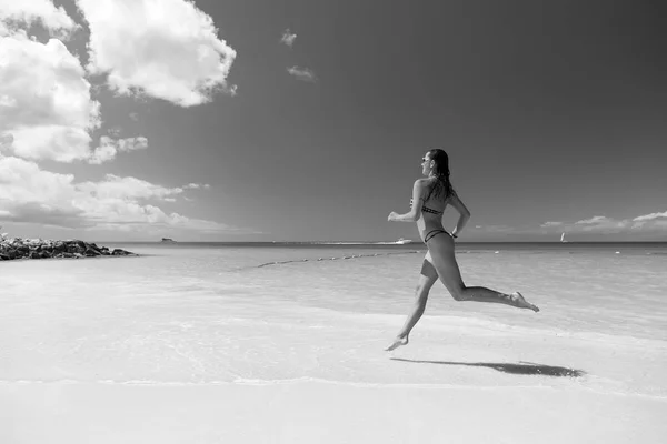 Girl with sexy body in swimsuit running on sea beach — Stock Photo, Image