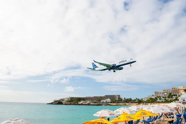 Philipsburg, Sint Maarten - January 24, 2016: jet flight low fly over maho beach. Plane land on cloudy sky. Airplane over people at blue sea. Wanderlust, travel and trip. Beach vacation at Caribbean — Stock Photo, Image
