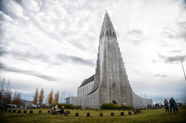 Reykjavik, Iceland - October 12, 2017: hallgrimskirkja church and people on cloudy sky. Christianity, religion and faith. Tall structure, architectural landmark on green grass, architecture