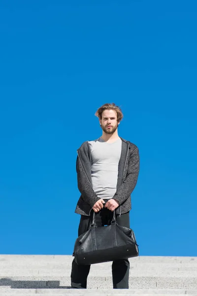 Hombre barbudo con bolsa en el cielo azul, futuro. Macho con bolsa de viaje en soleado al aire libre, vacaciones. Futuro, libertad, éxito. Guy modelo listo para las vacaciones, viaje. Moda para hombre con accesorio, estilo — Foto de Stock