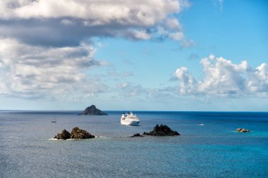 Cruise ship in blue sea on cloudy sky in gustavia, st.barts. Travel by water, discovery and adventure. Vessel and marine transport. Summer vacation and holiday destination clipart
