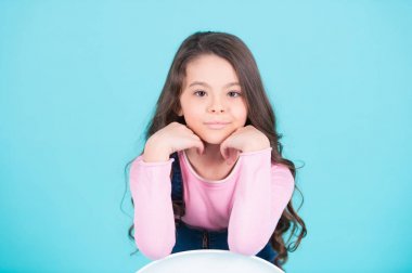 Uzun esmer saçlı, saç stiliyle gülümseyen bir çocuk modeli.