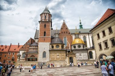 Krakow, Poland - June 04, 2017: Wawel cathedral with chapels on cloudy sky. People tourists on square infront catholic church. Architecture and design. Travelling on vacation clipart