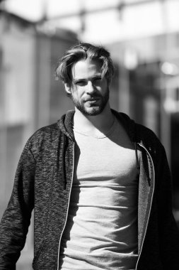 Gri tişörtlü adam güneşli bir günde yürüyor.