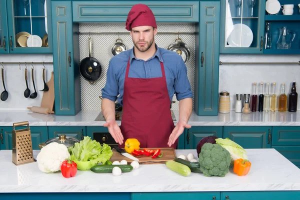 Muž bod na zeleninu na stole. Cook v kuchař klobouk a zástěru v kuchyni. Ingredience pro vaření jídla. Vegetariánské menu a zdravou stravu. Příprava jídla a vaření recepty — Stock fotografie