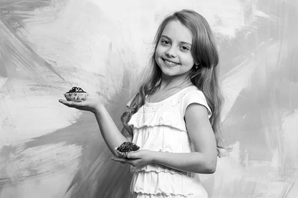 Menina sorrindo com cupcakes nas mãos — Fotografia de Stock