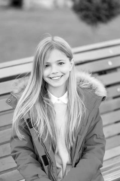 公園のベンチに座っている赤いコートの女の子 — ストック写真