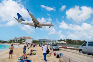 Philipsburg, Sint Maarten - 13 Şubat 2016: uçak arazi maho sahilde insanlar üzerinde. Uçak düşük anında bulutlu mavi gökyüzü. Jet Uçuş deniz üzerinde. Caribbean Beach Tatil. Yolculuk tutkusu, seyahat ve gezi