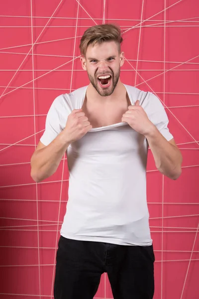 El hombre de moda tira del cuello de la camiseta con ira. Modelo de moda en estilo casual gritar sobre fondo rosa — Foto de Stock