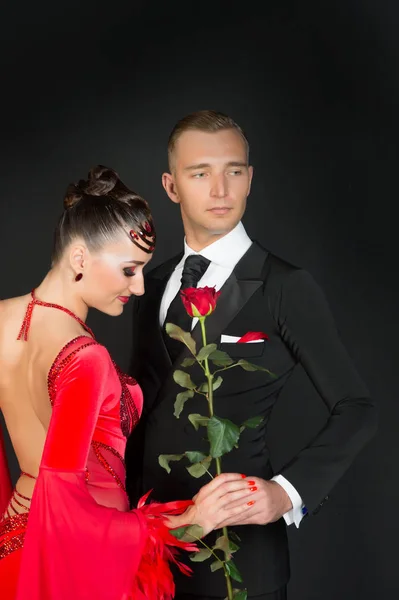 Mulher sensual e homem com flor de rosa. Mulher de vestido vermelho e macho de smoking. Uns bailarinos apaixonados. Celebração do dia dos namorados. Proposta de amor e conceito de data — Fotografia de Stock