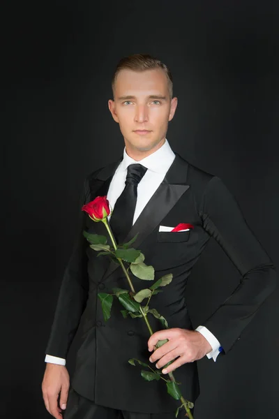 Homme en costume avec rose sur fond sombre . — Photo